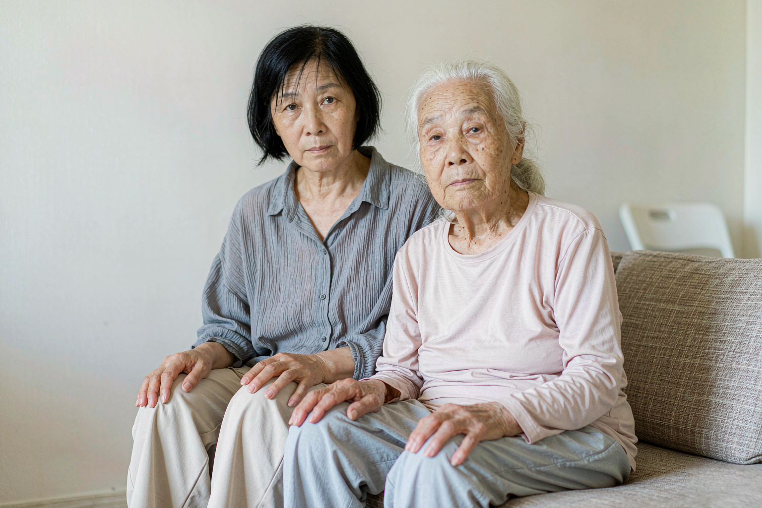 观察疼痛信号 家属俯身观察坐在轮椅上的认知症老人表情变化